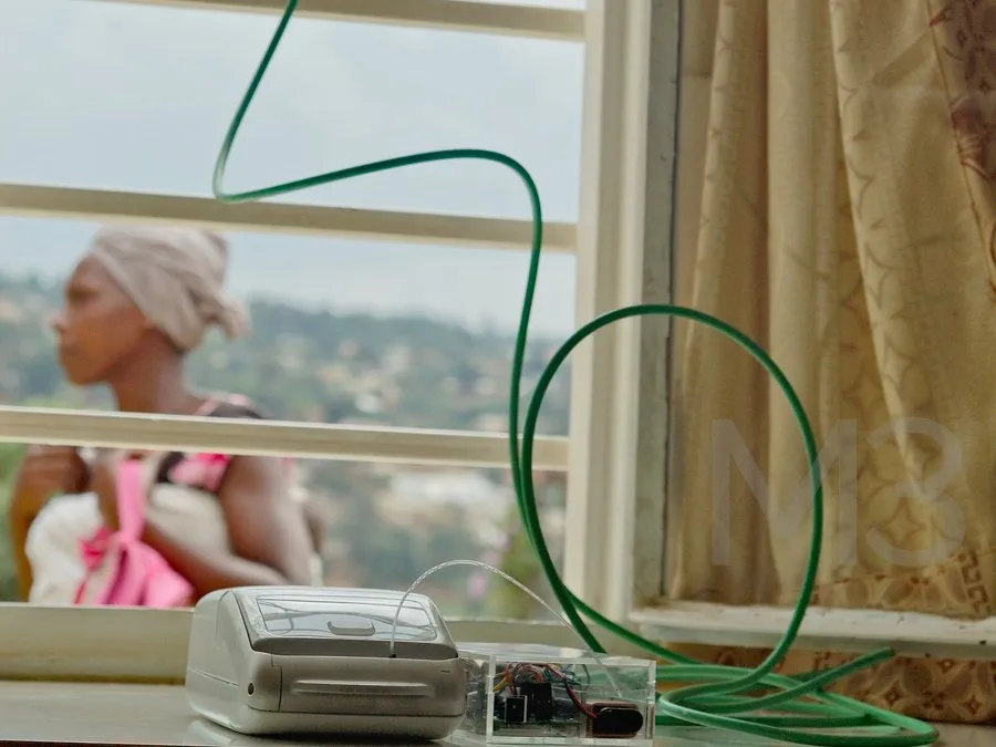 A point-of-care diagnostic device on a windowsill during field testing in Rwanda, with a green tube looping up to the window